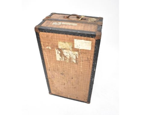 A vintage metal bound steamer trunk enclosing a fitted interior with wardrobe section to one side, the other side with drawer