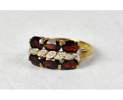 A 9ct yellow gold ring with a central twist line of tiny diamonds, between two rows of three claw set Mozambique garnets, siz