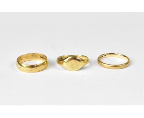 Three 9ct gold rings to include two band rings, both size K, and a small signet ring, size L, combined approx 5.2g (3).