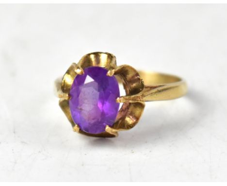 A yellow metal ring set with an oval amethyst in an open work floral mount, marks indistinct, size O, approx 2.7g.