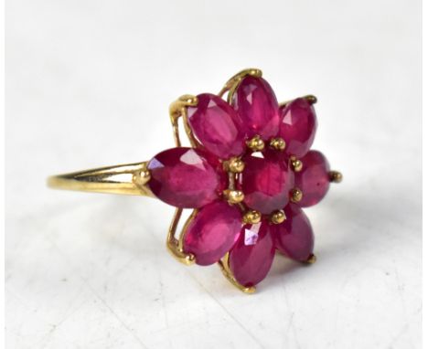 A 9ct gold and ruby ring, the fissure-filled ruby flowerhead comprising a central claw set round stone and eight oval petals,