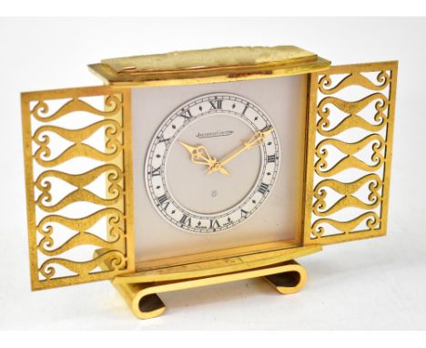 JAEGER-LECOULTRE; a gilt brass mantel clock, the pierced sliding doors enclosing a silvered face and chapter ring set with Ro