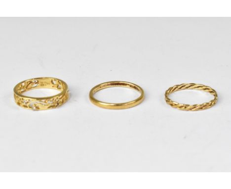 Three rings comprising a thin 9ct gold band, size N, a modern half eternity ring with open work floral pattern with four diam