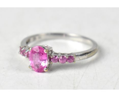 A 9ct white gold ring with central claw set cut oval pink sapphire flanked by three smaller claw set round sapphires, size P,