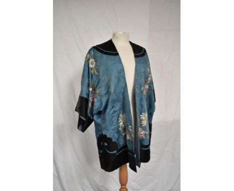 An exquisitely embroidered antique Chinese silk jacket in pale blue and black with pastel butterfly and flora detail.