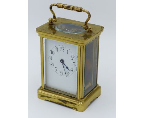 A BRASS CASED CARRIAGE CLOCK, TYPICAL FIVE GLASS FORM WITH VISIBLE ESCAPEMENT, WHITE ENAMEL DIAL WITH ARABIC NUMERALS.