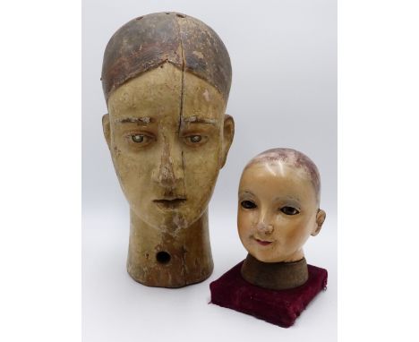A 19TH CENTURY CARVED WOOD  MANNEQUIN HEAD WITH PAINTED FEATURES TOGETHER WITH A HAND PAINTED WOOD DOLLS HEAD.  32 CM AND SMA