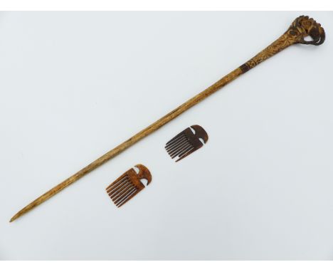 A LONG BONE HAIR PIN WITH STAINED AND CARVED DECORATION TOGETHER WITH TWO SMALL BONE COMB PENDANTS. THE PIN 39 CM LONG.