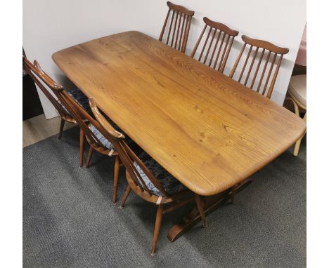 A golden Ercol dining table together with a set of six spindle back dining chairs, table 180 x 85 x 70cm.