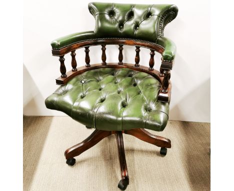 A mahogany and green leather button backed, revolving captains chair on wheels, slight damage to one button. H. 83cm.