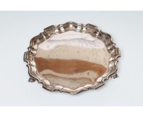 A SILVER SALVER, maker Viners, Sheffield 1937, of shaped circular form with pie-crust rim raised upon three knurl feet, 10" d