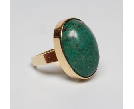 A MODERN DRESS RING, the oval cabochon polished green hardstone collet set to a plain square section shank, stamped 750 (Est.