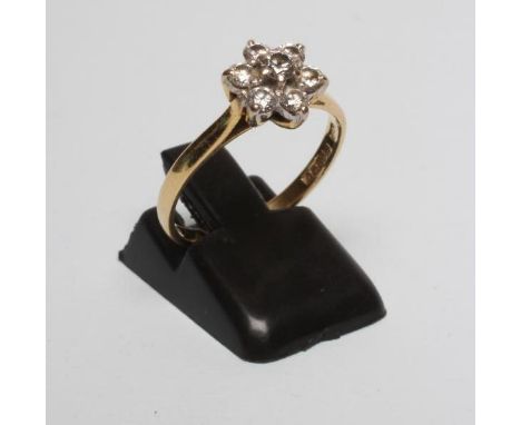 A DIAMOND CLUSTER RING, the seven round brilliant cut stones claw set in a flowerhead to a plain 18ct gold shank, Birmingham 