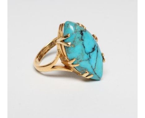 AN ARTS AND CRAFTS DRESS RING, the cabochon polished eliptical turquoise matrix claw set to open shoulders and plain shank st