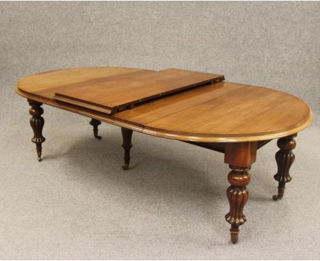 A VICTORIAN MAHOGANY EXTENDING DINING TABLE, the moulded edged D ended top with three separate leaves and pull out action, ra