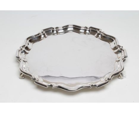 A SILVER SALVER, maker William Suckling, Birmingham 1956, of shaped circular form with pie-crust rim raised upon three acanth
