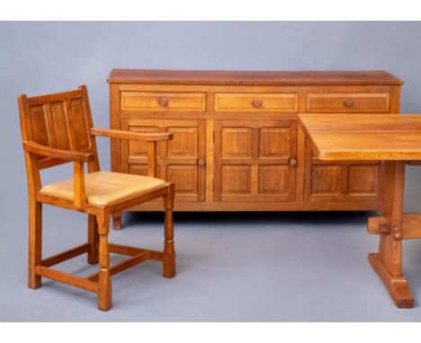 A COLIN ALMACK ADZED OAK DINING SUITE comprising multi panelled sideboard, with three frieze drawers over three cupboard door