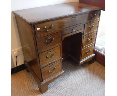 A GEORGE III MAHOGANY KNEEHOLE DESK with an arrangement of drawers and a recessed cupboard on bracket feet 35" wide