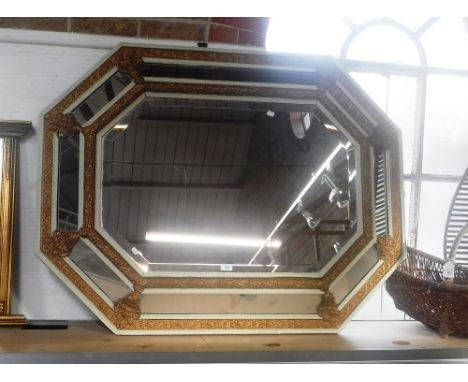 AN OCTAGONAL WALL MIRROR of cushion form with pressed metal mounts, circa 51" x 40"