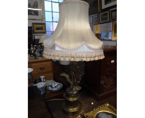 A GILT METAL TABLE LAMP in the form of an eagle, with a fringed silk shade