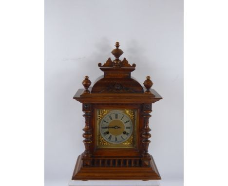 An Edwardian Carved Oak Cased Mantel Clock, the clock having a stamped Junghans chiming movement with silvered chapter ring a