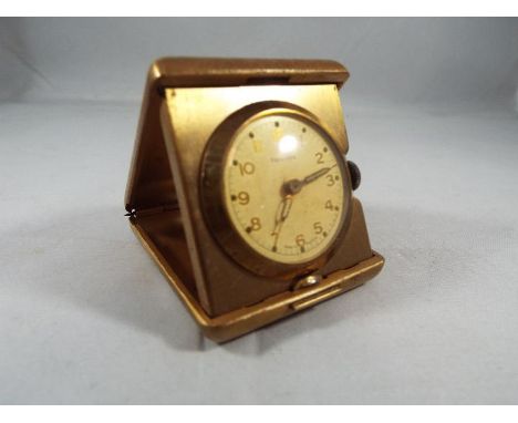 A yellow metal purse watch/ small travelling clock, cushion form case with diamond design engine turning, applied crown decor