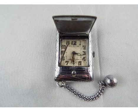 An Art Deco styled cushion form purse watch/ clock, the case with engine turned decoration and having a small golf ball on a 