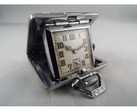 A small purse watch/ clock in a 36mm square cushion form case bearing the remnants of cream enamel with erotic scenes, the wa