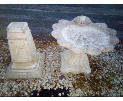 A reconstituted stone bird bath in the form of a shell and a garden ornament