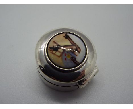 A silver pill box with painted enamel