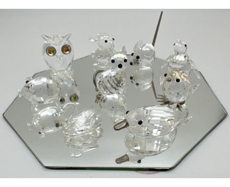 A collection of small Swarovski crystal animal figures on a mirrored stand. All etched with the square shaped mark. Tallest a