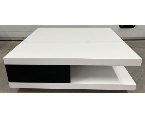 A modern black and white square shaped low coffee table with gloss finish. with 2 black drawers and lower shelf design. 