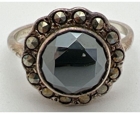 A vintage silver dress ring set with a central round cut hematite stone, surrounded by 14 marcasite stones. Inside of band ma