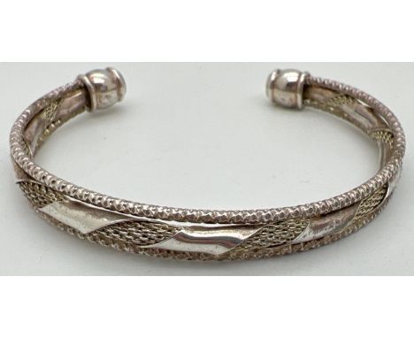 A decorative 3 band cuff bangle with twist design to middle band. Silver marks to one end. Total weight 17.6g. 