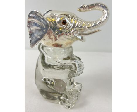 A clear glass bottle/decanter modelled as an elephant with a silver plated lid and rim. With brown glass eyes. Approx. 13.5cm