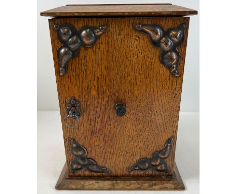 An early 20th century oak smokers cabinet with Arts &amp; Crafts style copper panels applied to door. 2 interior draws with d