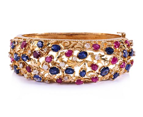 A RUBY, SAPPHIRE AND DIAMOND HINGED BANGLE Featuring oval cut rubies and blue sapphires totalling approximately 11.50 Cts, mo