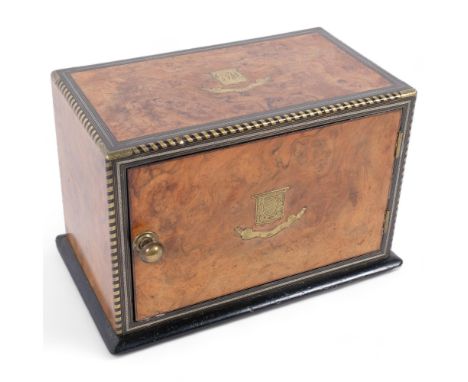 A Victorian burr-walnut and brass-bound table-top box, single hinged door revealing a fitted shelf interior, with an inlaid b