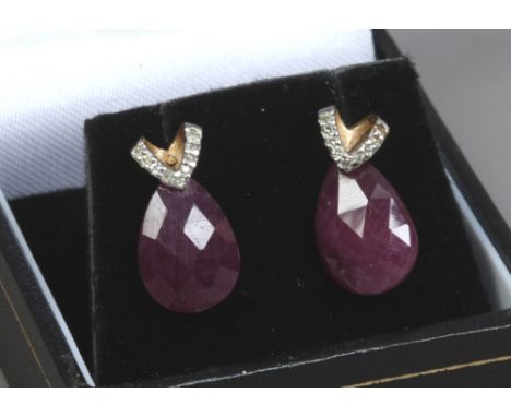 A pair of 9ct gold earrings set with diamonds and with faceted synthetic ruby droplets.