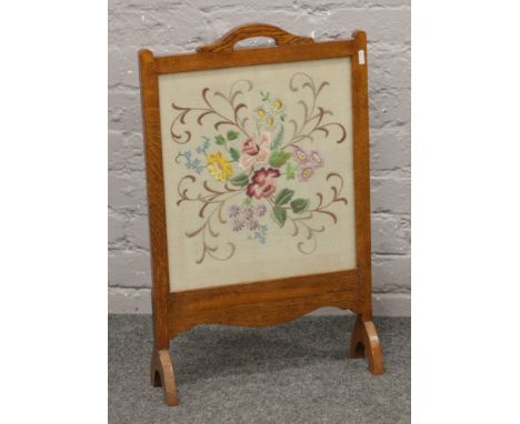 An oak cased firescreen with embroidered panel.