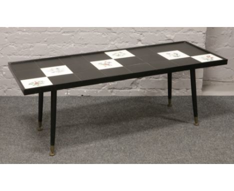 A tile top coffee table on tapering supports.