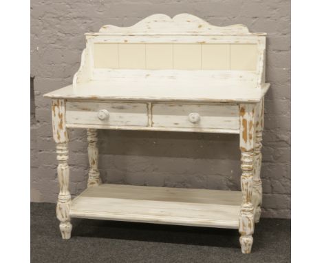 A painted washstand raised on turned supports with tile splash back and two drawers.