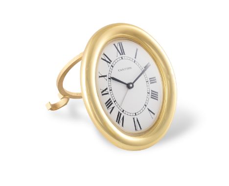 AN DESK CLOCK BY CARTIER, the oval gold plated desk clock with quartz movement, with alarm clock, white dial with Roman numer