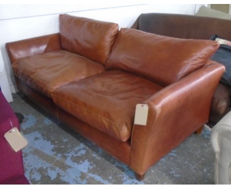 SOFA, two seater in tanned leather on block supports, 205cm L. 