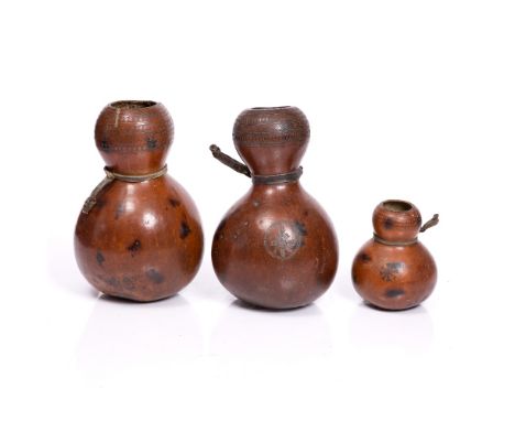 THREE ETHIOPIAN GOURDS, with incised geometric pattern and leather strap handles, one with woven patch work repairs, largest 
