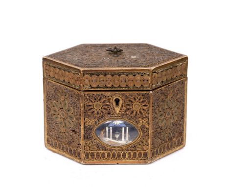 A GEORGE III HEXAGONAL PAPER SCROLL TEA CADDY decorated with formal foliate designs, the central panel with oval glass plaque