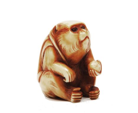 AN EARLY 20TH CENTURY JAPANESE IVORY NETSUKE, carved as a seated monkey, wearing a jacket and holding a ball, 3.5cm high