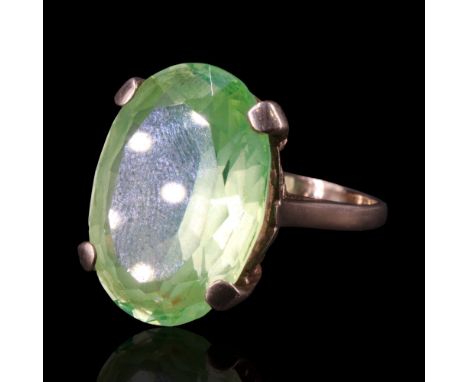 A green topaz and 9 ct gold dress ring comprising an oval-cut stone, claw-set on the open bow-tied gallery on a 9 ct gold sha
