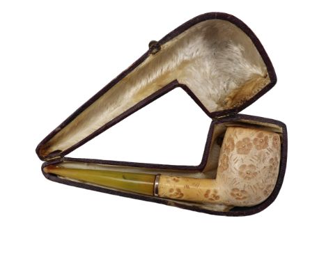 An early 20th Century meerschaum tobacco pipe having a gilt metal collar, the bowl decorated with engraved flowerheads, in fi