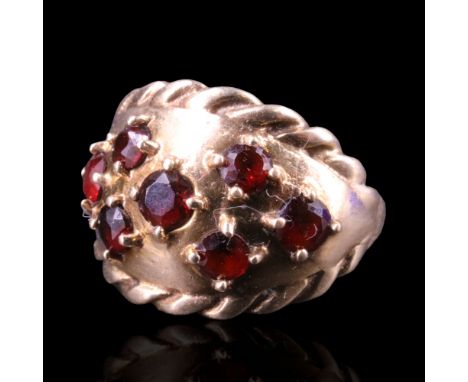 A garnet finger ring comprising an open arrangement of seven round-cut stones, claw-set between cables on a convex 9 ct gold 